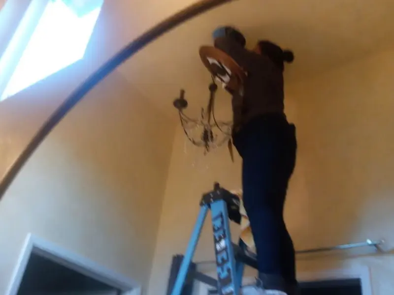 Electrician installing a chandelier in a Monroe residence